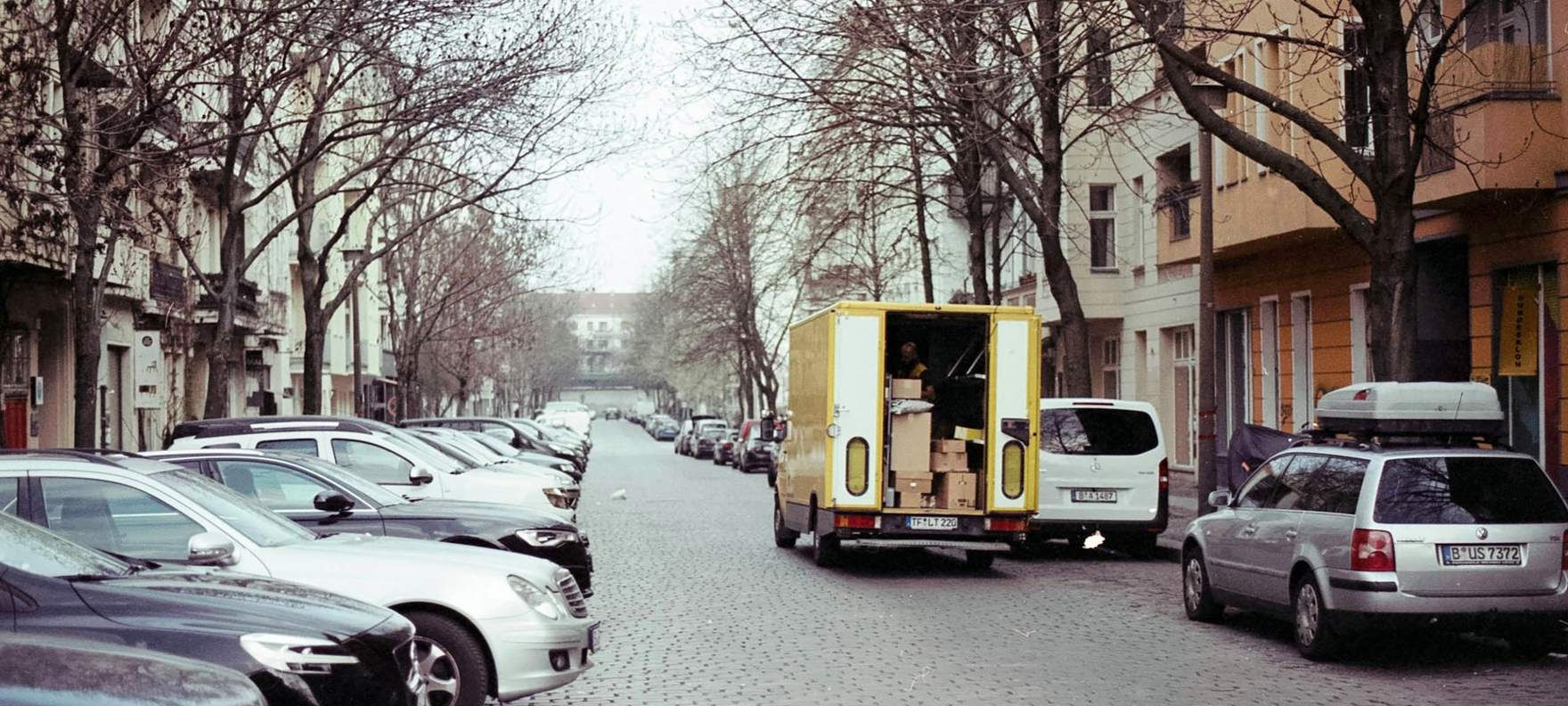 Umzugswagen mit offenen Hecktüren wird in einer von Altbauten gesäumten Straße beladen
