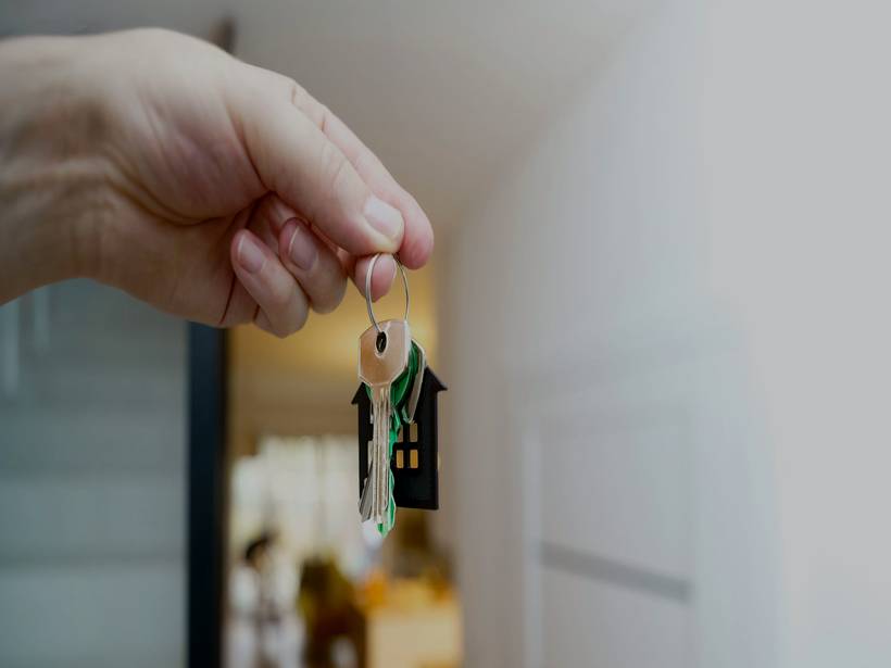 Hand hält den Schlüsselbund der neuen Wohnung vor der geöffneten Tür